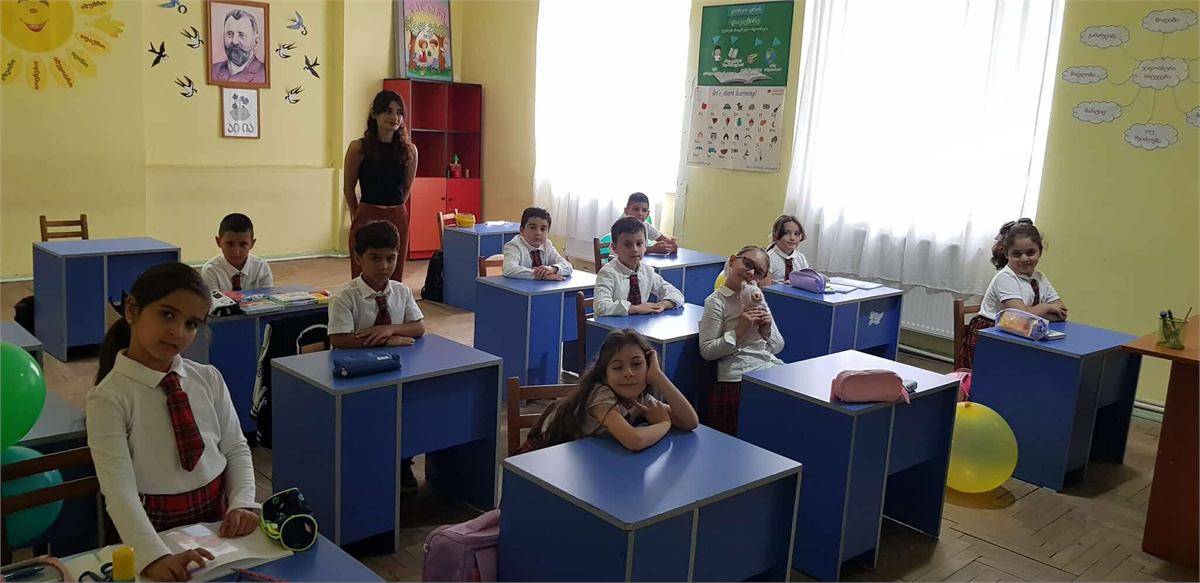 დაწყებითი კლასი ლურჯ მერხებთან, მასწავლებელი კლასის წინ